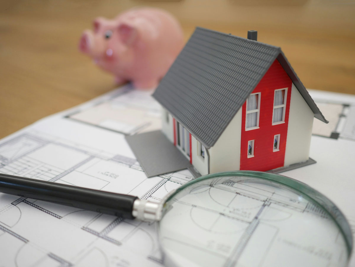 piggy bank with model home on top of floorplan